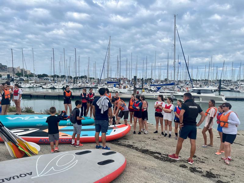 Une vingtaine de personnes et 3 paddles géants au sol.