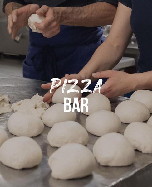 Des boules de pâtes à pizza derrière l'écriture "Pizza Bar"