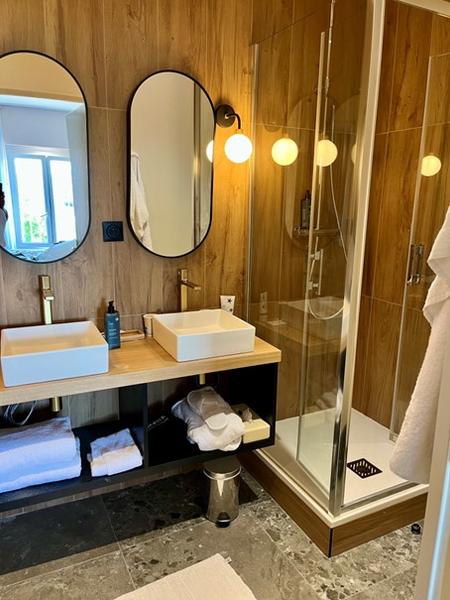 Une salle d'eau avec cabine de douche, double vasque, deux miroirs.