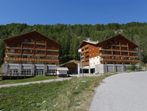 Vue de la résidence, deux bâtiments sur plusieurs étages reliés par une aile centrale avec réception, cadre montagne