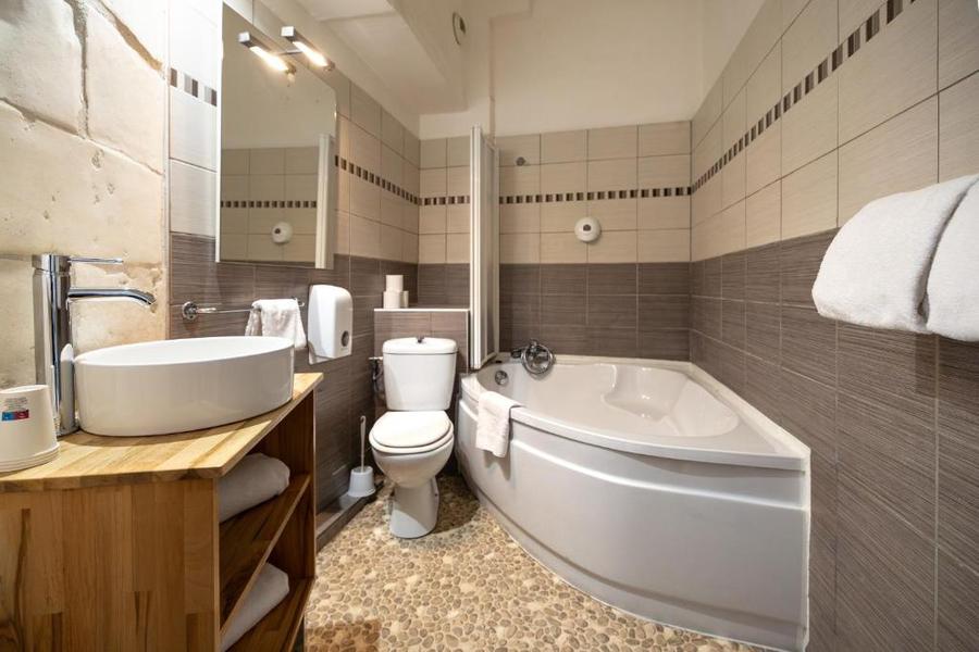 une salle de bain avec baignoire d'angle, toilette et lavabo.