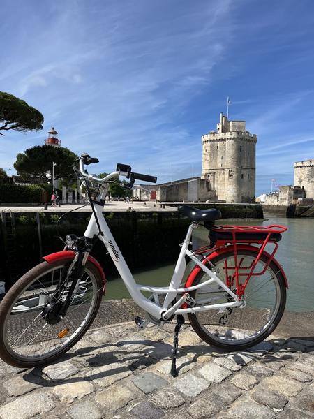 Un vélo blanc et rouge devant la Tour Saint-Nicolas.