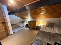 Chambre mansardée avec deux lits simples, commode et chevets