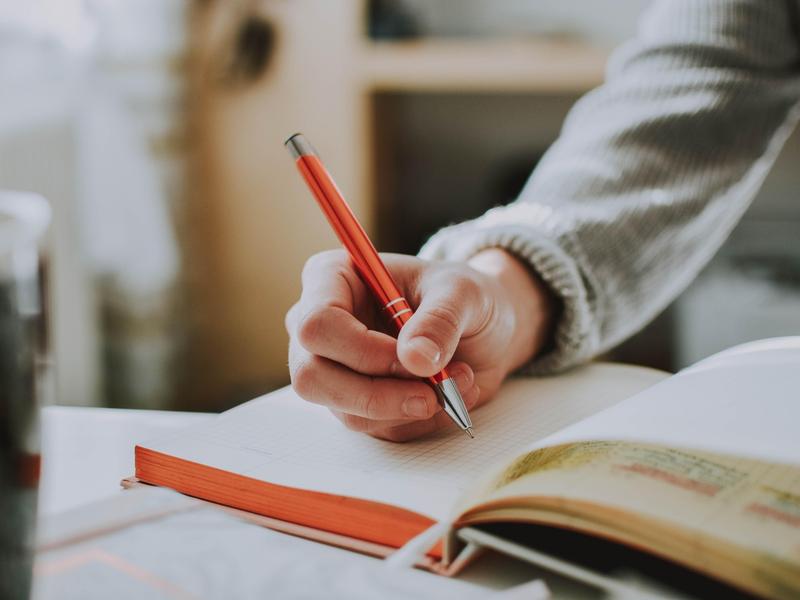 Une personne écrit sur un cahier