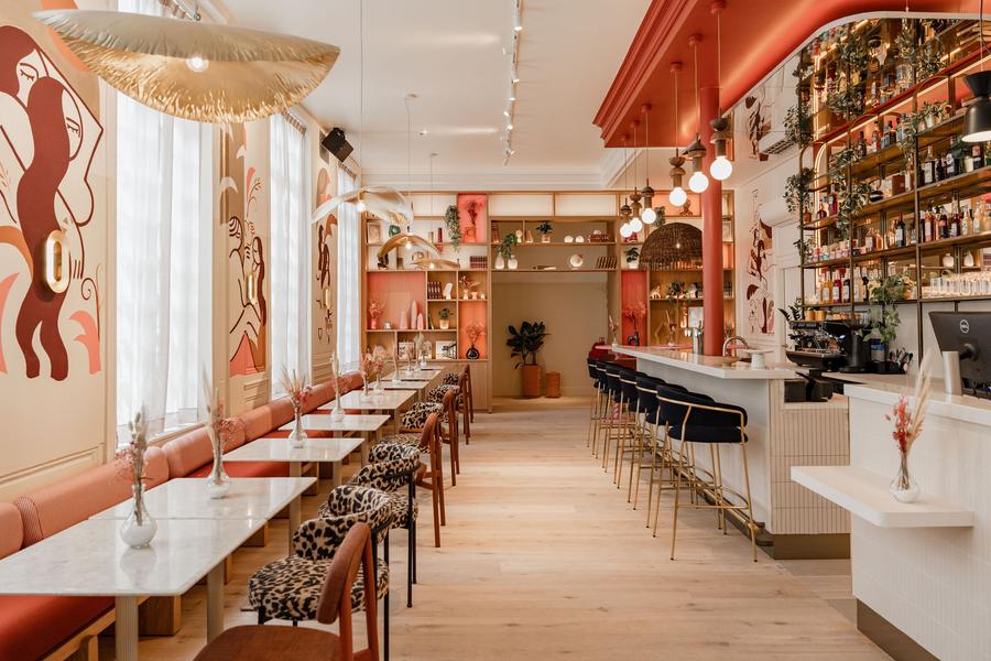 La salle du restaurant, avec des tables, des chaises et une grande banquette le long du mur.