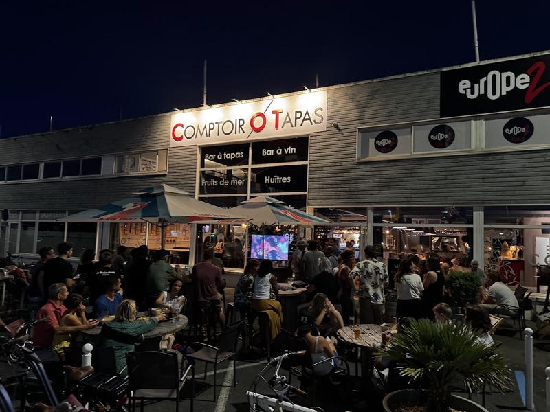La terrasse extérieures de nuit, avec des clients aux tables.