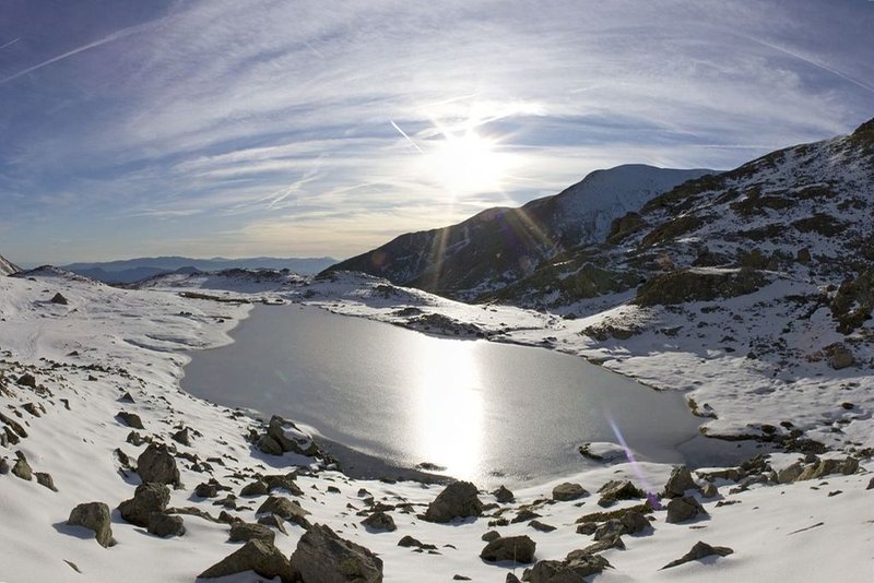 En contre-jour de lumière d'automne, un des lacs de Millefonts en début de phase de gel.