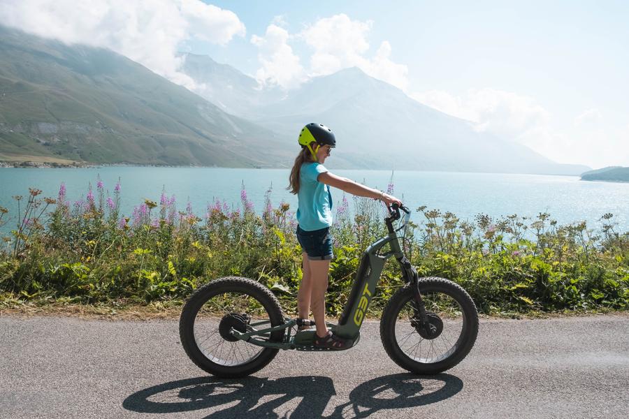 Une jeune fille en trottinette électriqueau bord du lac du Mont Cenis Une jeune fille en trottinette électriqueau bord du lac du Mont Cenis