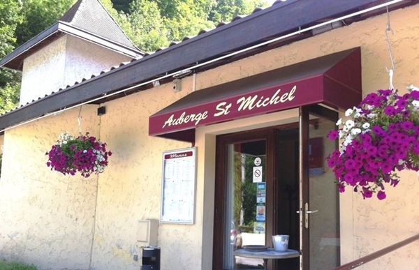 Ce restaurant possède une façade de couleur pastel. Une porte d'entrée, surmontée d'une marquise, est encadrée de deux fenêtres. Des plantes en pots décorent l'entrée.