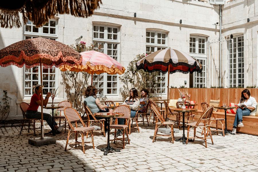 la terrasse dans la cour, avec des tables et des parasols.