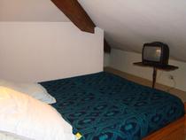 Chambre à coucher sous combles avec lit double, TV, ameublement bois
