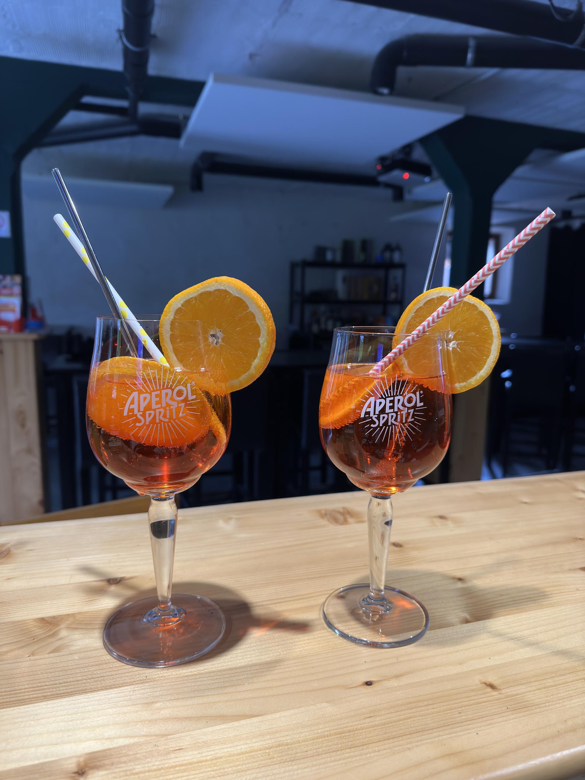 2 verres de sprizt servis avec une rondelle d'orange et une paille.