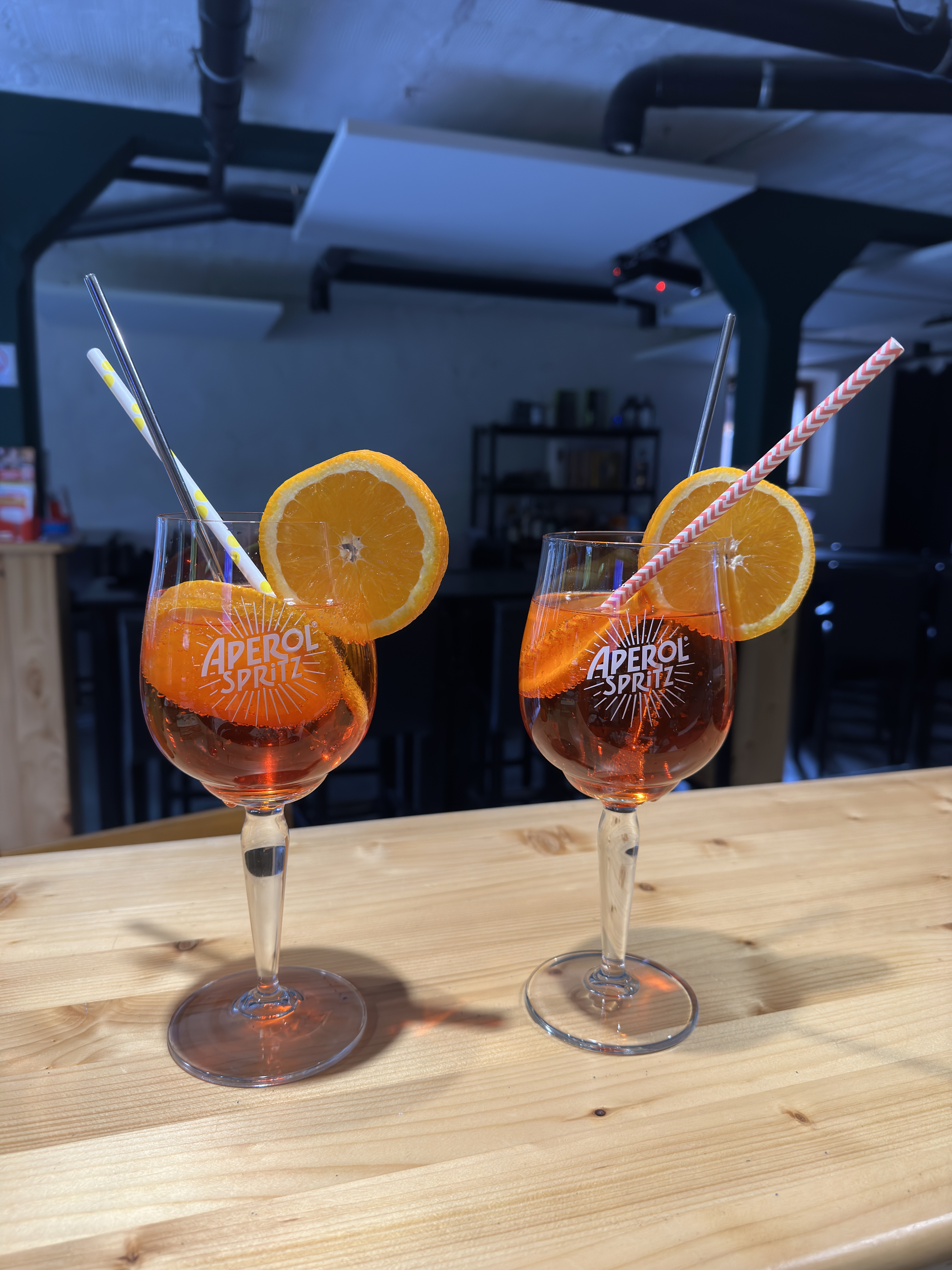 2 verres de sprizt servis avec une rondelle d'orange et une paille.