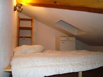 Chambre à coucher sous combles avec lit double, ameublement bois, espace de rangement
