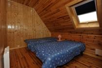 Chambre à coucher sous combles avec deux lits simples, velux, ameublement bois