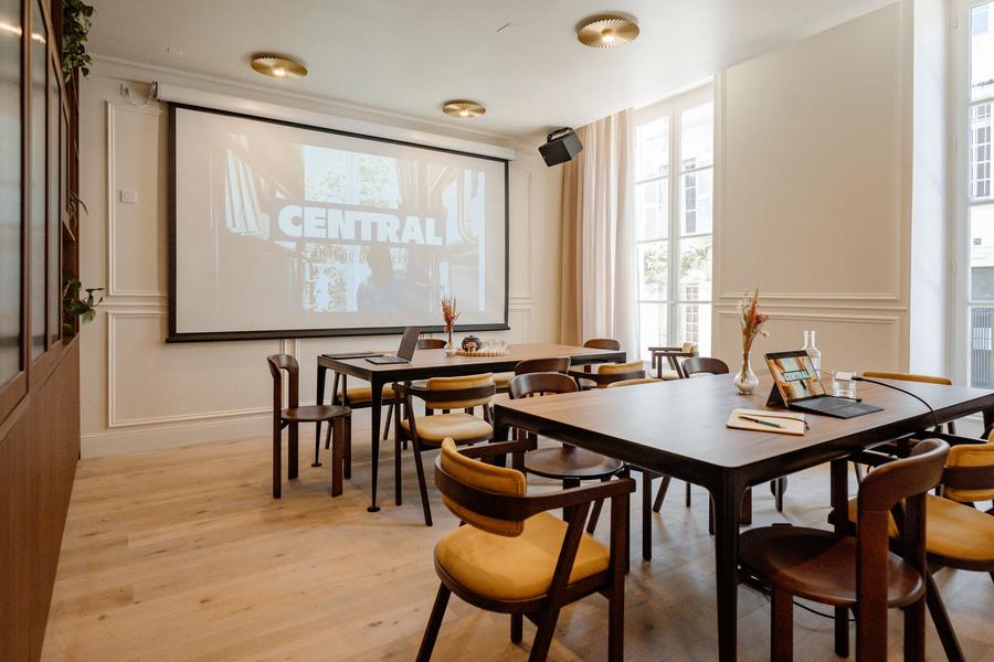 Une salle de réunion / séminaire avec deux grandes tables, des chaises, et un vidéoprojecteur.