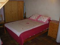 Chambre à coucher avec lit double, ameublement bois, sol carrelé