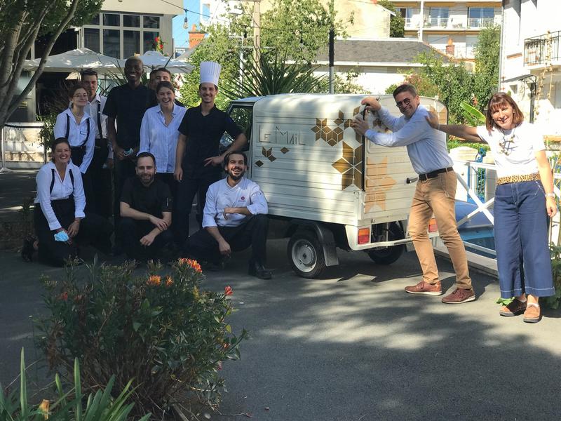 Toute l'équipe du restaurant posant en extérieur, contre une voiturette logotée "Le Mail"