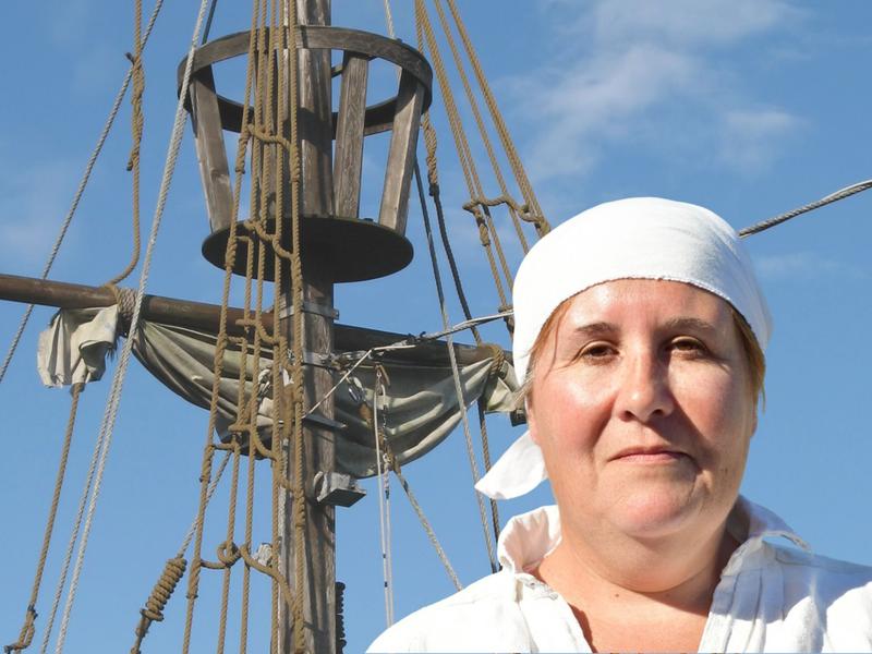 Une femme se tient devant un mât de bateau