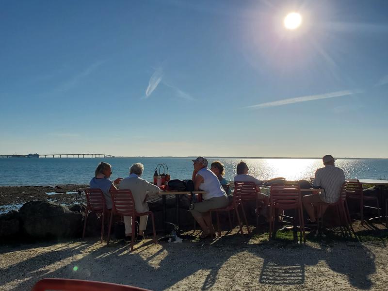 Des personnes assises à des tables en front de mer.