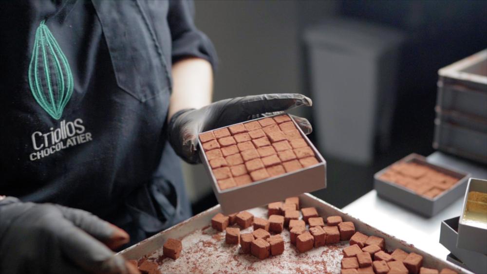 Un chocolatier remplissant une boite de "Pavés Rochelais".