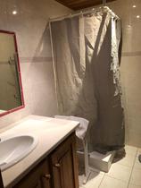 Salle d'eau avec bac à douche, rideau, évier, carrelage