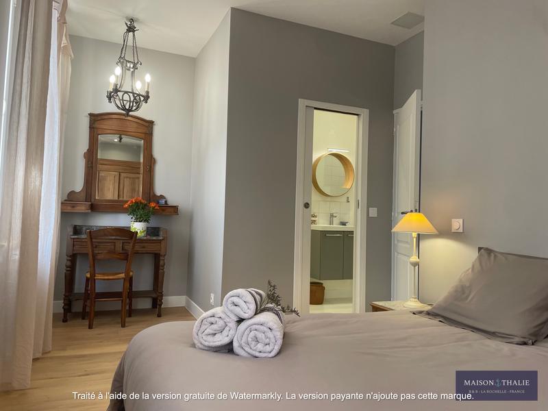 Une chambre avec un lit et un bureau, donnant sur des toilettes.