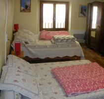 Chambre à coucher lumineuse avec deux lits doubles, ameublement bois, parquet au sol, fenêtre