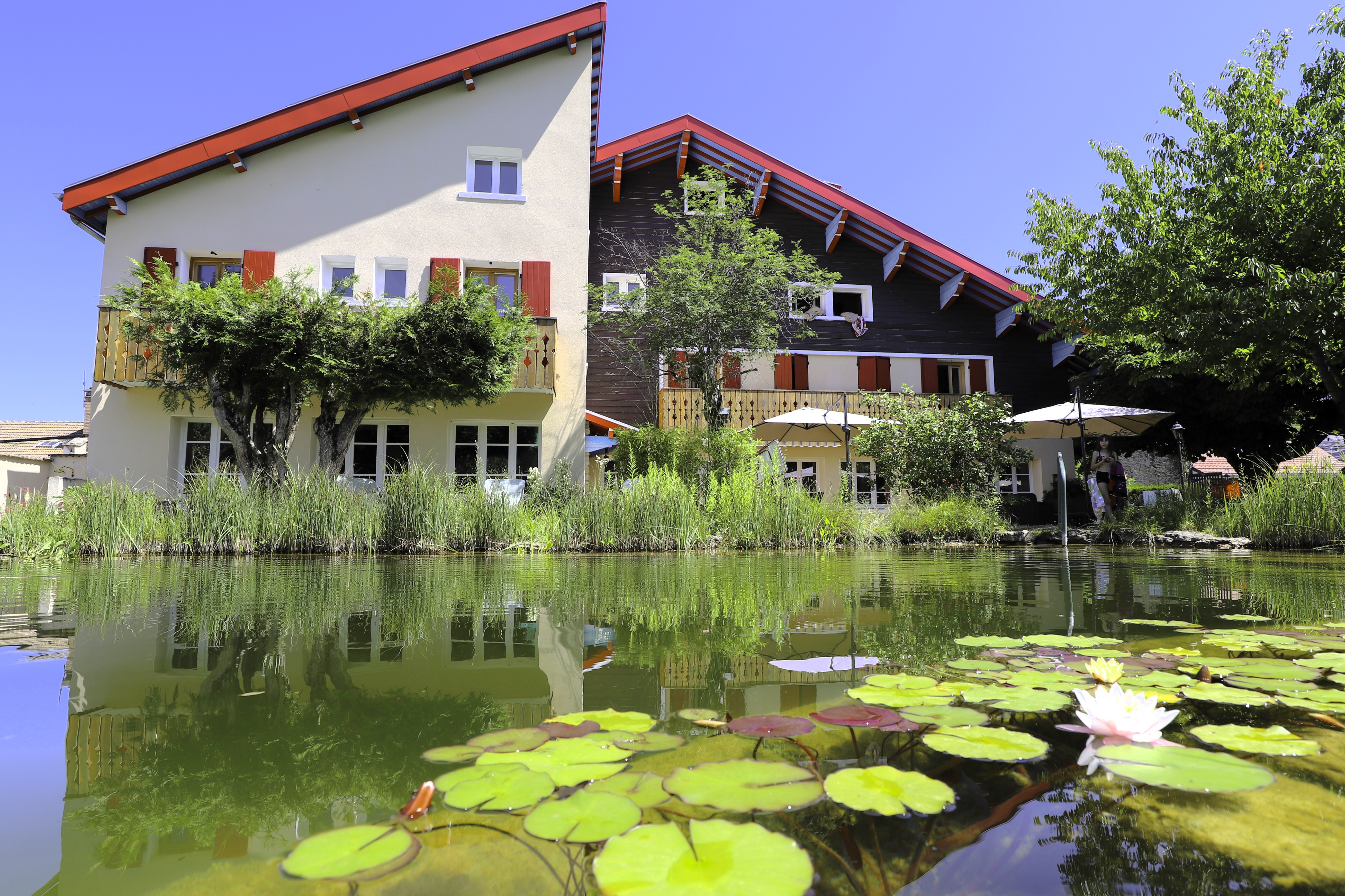 Piscine naturelle au premier plan avec l’établissement en arrière plan sous un ciel dégagé