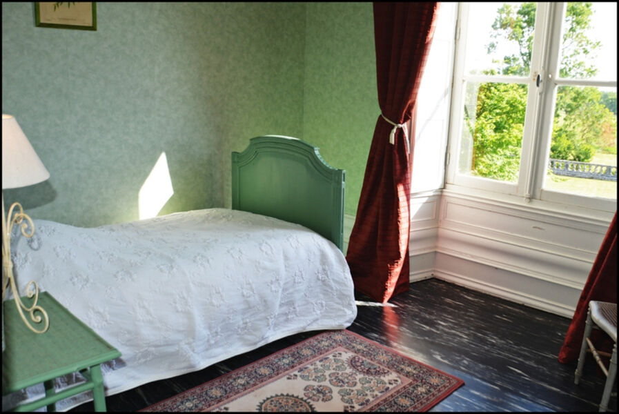 Lit simple et grande fenêtre, chambre dans les tons vert pâle