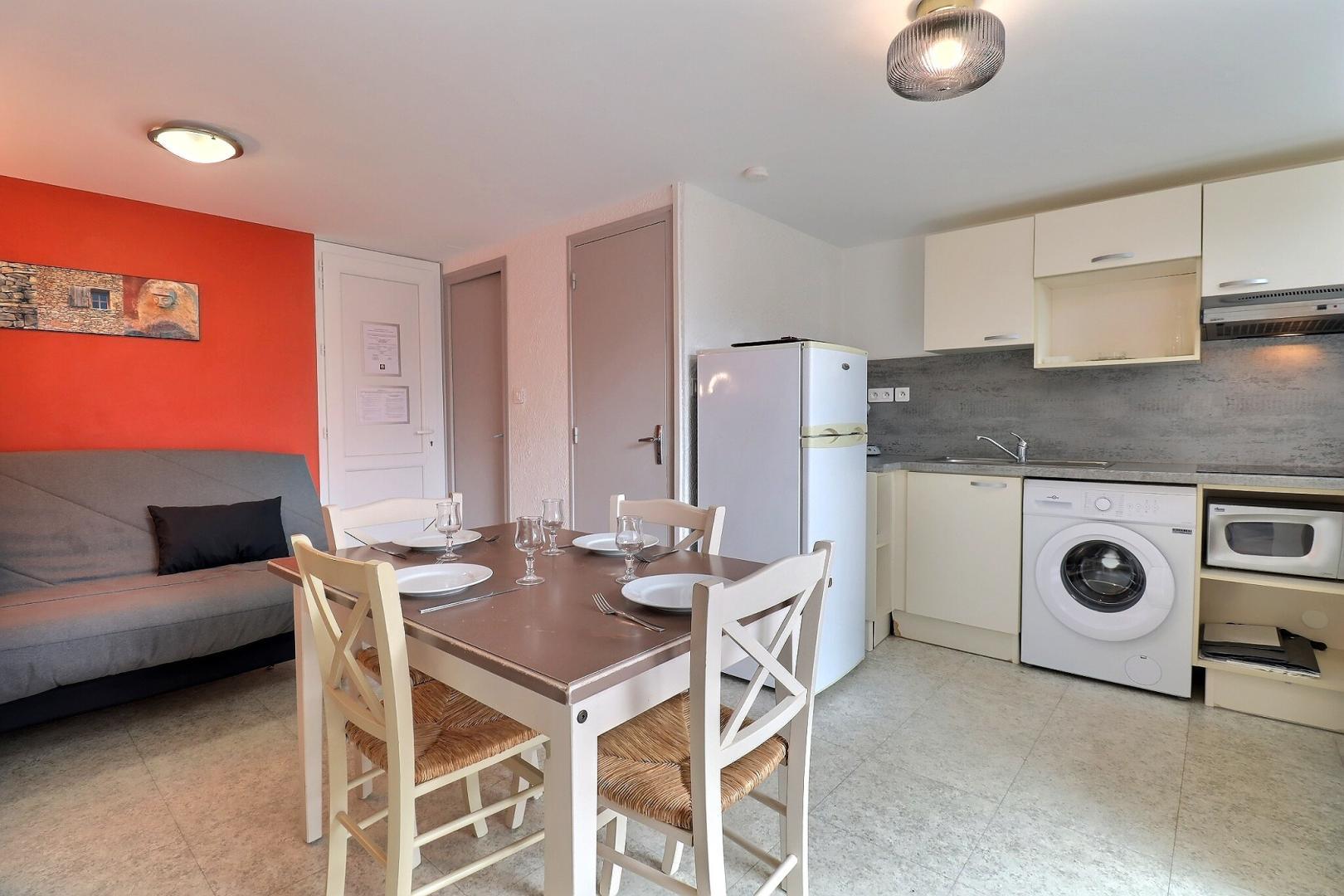 Pièce à vivre avec coin cuisine, espace repas, canapé convertible (clic-clac 1x140), accès direct à la terrasse privative