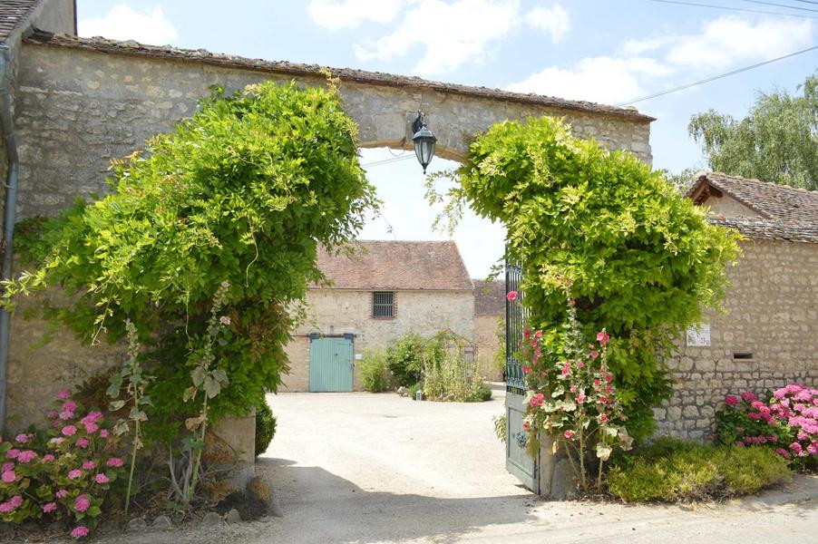 Vue de la route, porche d'entrée, la glycine court sur le mur