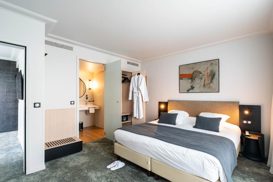 Une chambre avec un lit double, une porte ouverte vers la salle d'eau.
