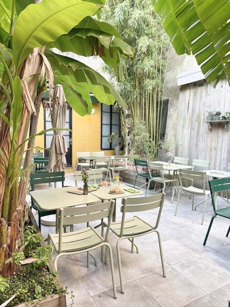 Le patio végétalisé, avec des tables et chaises métalliques.
