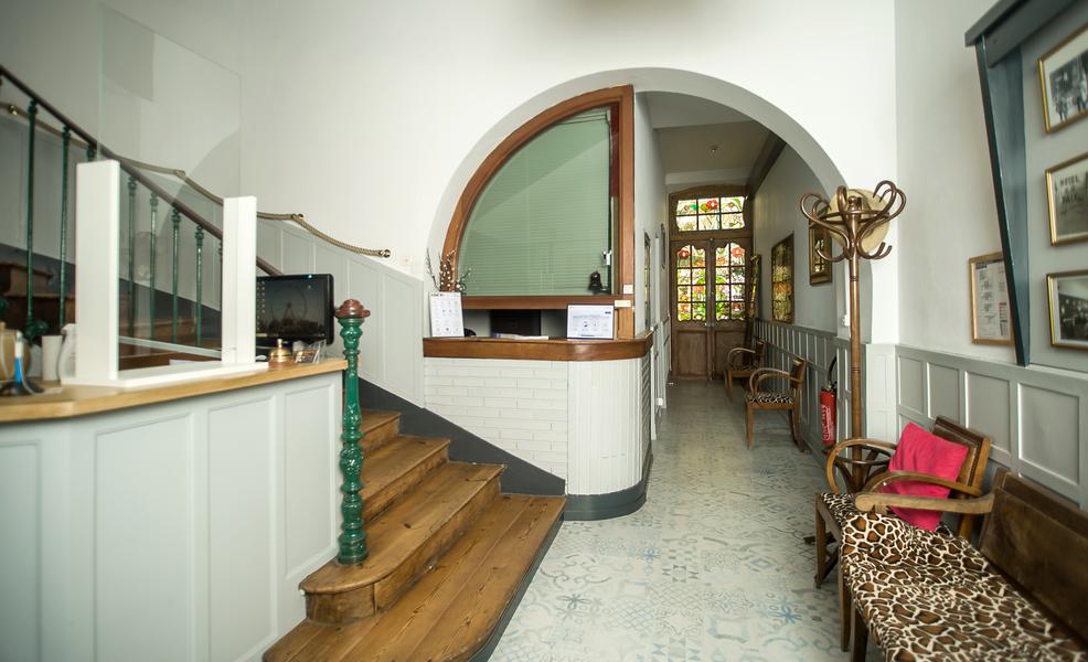 L'entrée de l'hôtel avec le comptoir, des fauteuils motifs girafes, un escalier menant à l'étage.