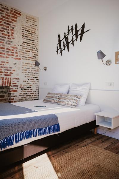 Une chambre avec lit double, mur en briques.