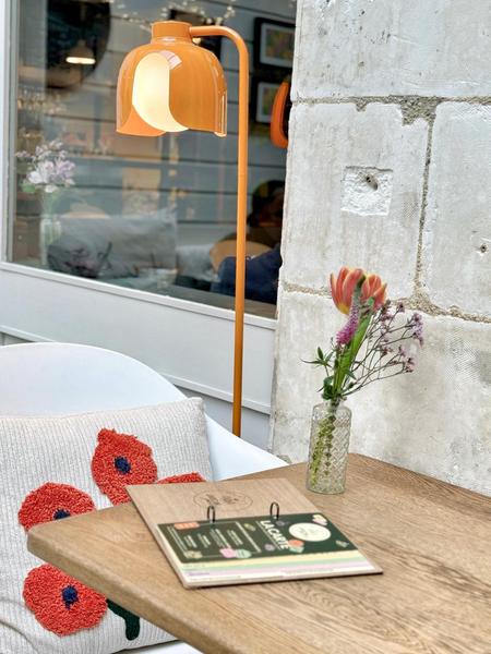 Une table éclairé par une lampe sur pied sous la véranda.