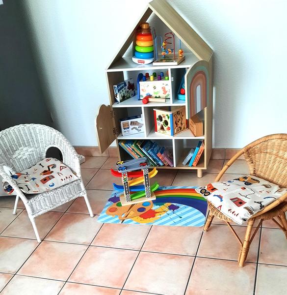 Coin enfant avec deux petits sièges en osier, petit meubles avec jouets.