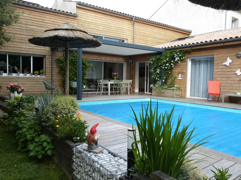 La piscine extérieure découverte, sur la terrasse en bois, accolée à la maison.