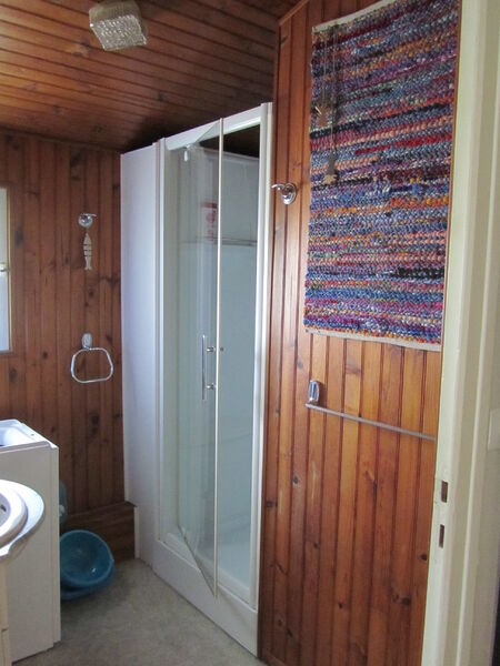 Salle d'eau avec douche, murs en lambris.