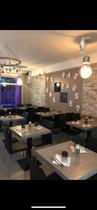 Salle de restaurant lumineuse et moderne avec tables et chaises, fenêtre au fond donnant sur la galerie marchande