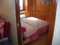 Chambre à coucher lumineuse avec lit double, ameublement bois, parquet au sol, fenêtre