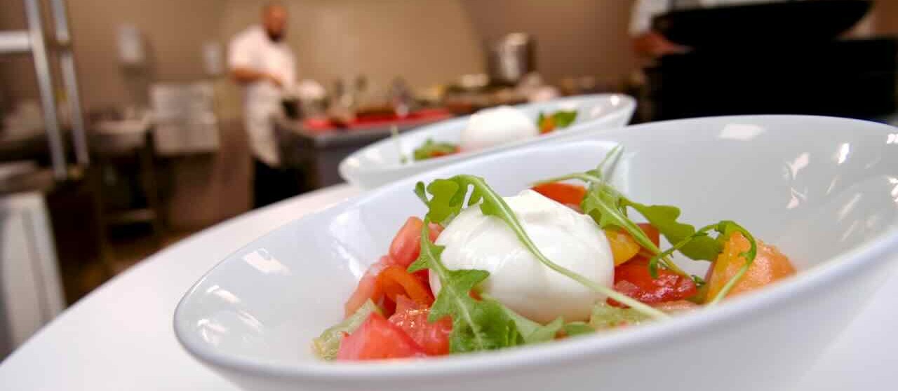 Entrée composée de tomates, burrata et roquette.