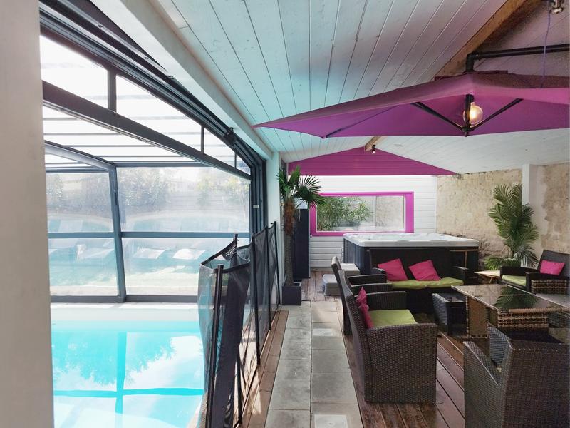 Un espace sous véranda donnant accès à la piscine couverte, avec des fauteuils, jaccuzzi.