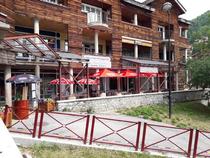 Vue du restaurant depuis l'extérieur de la galerie marchande. Terrasse extérieure avec parasol. Panneau avec inscription : "Pourquoi pas, spécialités fromagères"