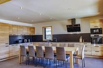 Grande cuisine lumineuse et moderne avec table à manger, TV, fenêtre, ameublement bois et sol carrelé