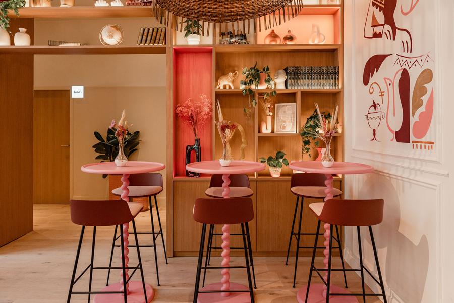 Trois tables hautes roses et 6 chaises hautes dans un coin du restaurant.