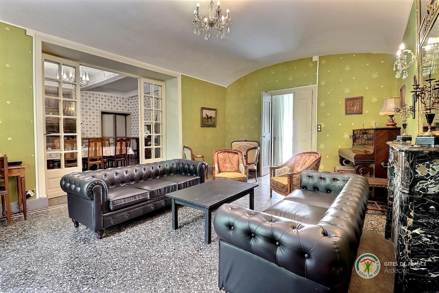 Salon avec deux canapés, TV écran plat et piano