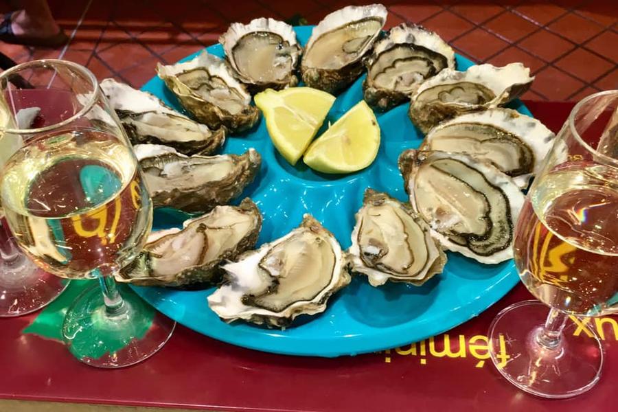 Une assiette d'huitres et deux verres de vin blanc.