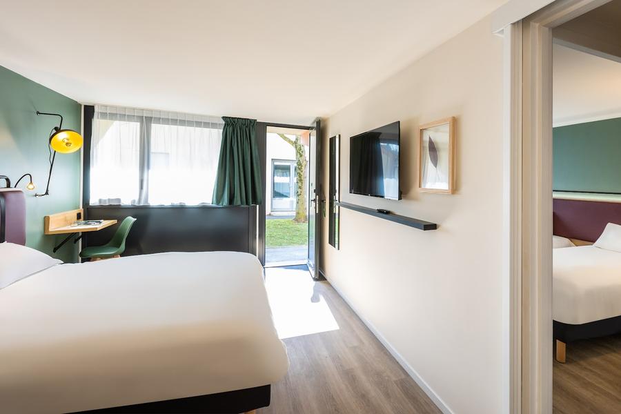 Une chambre en rez de chaussée avec lit double, une porte donnant sur l'extérieur est ouverte.